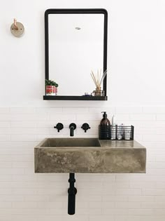 a bathroom sink sitting under a mirror in front of a wall mounted faucet