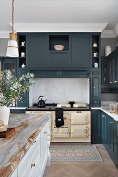 a kitchen with blue cabinets and marble counter tops, an oven and stove top in the center