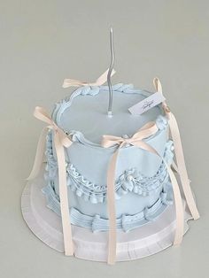 a blue cake sitting on top of a white plate with ribbon around the edges and a candle in the middle