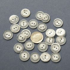 a pile of buttons sitting on top of a table next to a penny coin in front of them