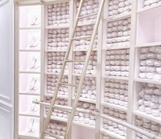 a room filled with lots of white shelves covered in stacks of shoes and ladders