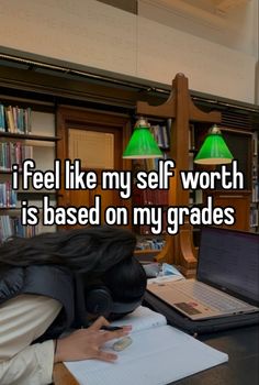 a girl is asleep on her desk in front of a laptop and bookshelf