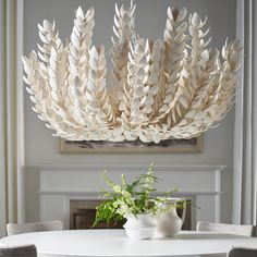 a white table topped with a vase filled with flowers next to a large wooden chandelier