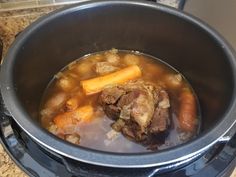 a pot filled with stew and carrots on top of a counter