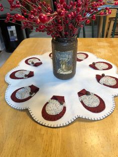 a vase filled with red berries sitting on top of a table next to a white doily