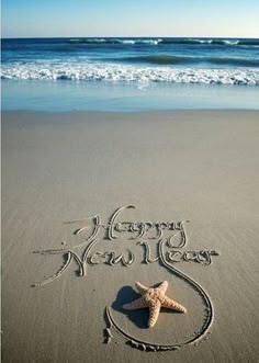 a happy new year message written in the sand at the beach with a starfish