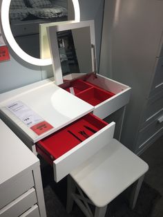 a white vanity with red drawers and mirror