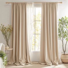 a living room filled with furniture and a window covered in beige drapes next to a potted plant