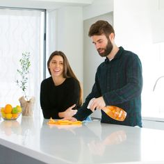 a man and woman in the kitchen with orange juice