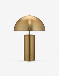 a gold table lamp on a white surface with a light bulb in the shape of a mushroom