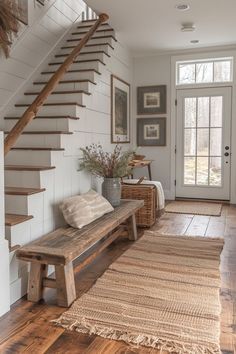 a wooden bench sitting under a stair case in a living room next to a door