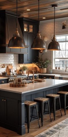 a kitchen island with stools in front of it and lights hanging from the ceiling