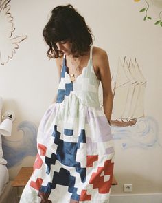 a woman in a colorful dress standing next to a wall with a ship painted on it