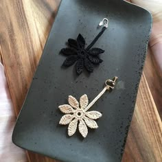 a black and gold plate with a key chain on it next to a flower brooch