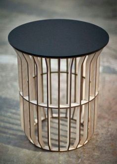 a round table with black top sitting on the ground next to a metal caged wall