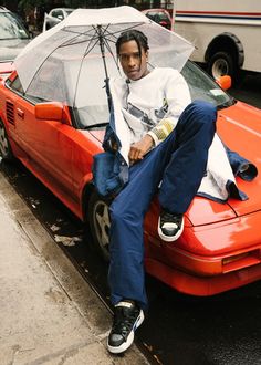 a man sitting on the hood of a car holding an umbrella