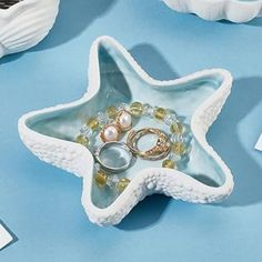 a star shaped dish with rings and pearls in it on a blue surface next to other dishes