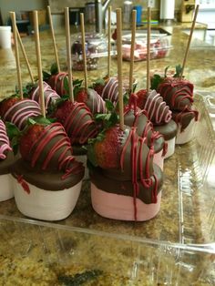 chocolate covered strawberries are arranged in small cups on a counter with toothpicks sticking out of them