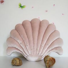 a pink scallop shell sitting on top of a table next to a seashell