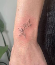 a small tattoo on the wrist of a woman's left arm, with a bird flying above it