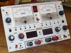 an analog multimeter sitting on top of a wooden table next to other electronic equipment