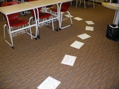 papers are scattered on the floor in an empty room with red chairs and desks