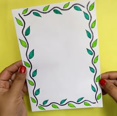 two hands holding up a piece of paper with green leaves on it and the bottom half of