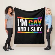 two women holding up a black towel that says i'm gay and i slay