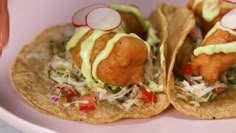 two fish tacos are on a pink plate