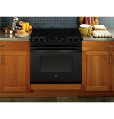 a black stove top oven sitting in a kitchen next to wooden cabinets and counter tops