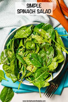 spinach salad in a white bowl on top of a blue napkin