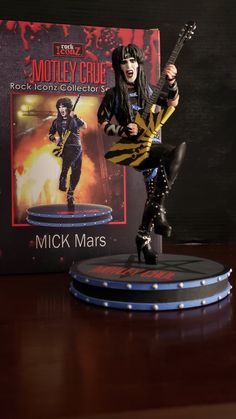 an action figure is posed next to a book cover and guitar hero figurine