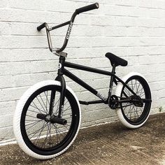 a black and white bmx bike parked in front of a brick wall with no wheels