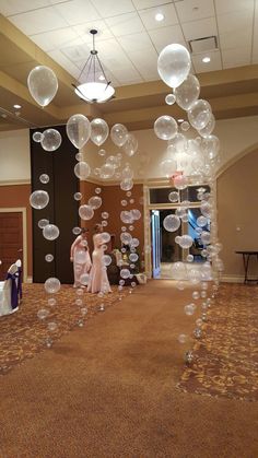 some people are standing in a room with many bubbles