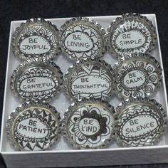 twelve bottle cap magnets with sayings on them in a white cardboard box that says be patient, be loving, be gentle