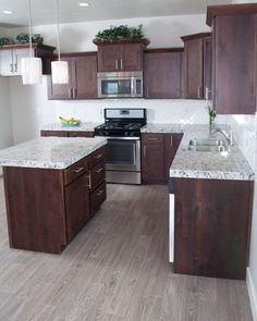 an empty kitchen with wooden cabinets and stainless steel appliances in the center, along with white marble counter tops