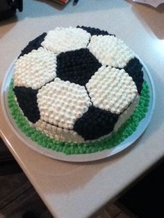 a cake with black and white frosting in the shape of a soccer ball on a pink plate