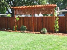 a wooden fence in the middle of a yard with plants growing on top of it