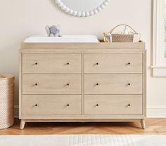 a baby's room with a dresser, mirror and teddy bear on the wall