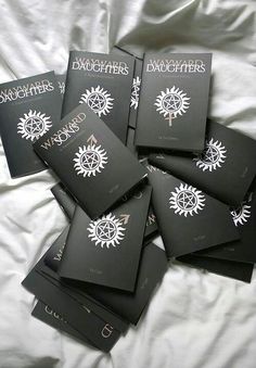 six black books with white writing on them sitting on top of a bed next to each other