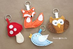 four felt key chains with different designs on them, including an owl, fox, and mushroom