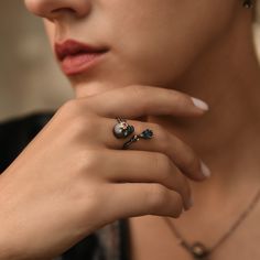 A little macabre, a lot funky, this Muerto ring laughs at the dark symbolism behind the skull. This symbolism points towards our own mortality, but amongst this inescapability, there is always time for gemstones. The teardrop-shaped London Topaz and the red flower studying the skull's eye inject a burst of colour into the dark themes running through the ring. Perfect match to our Muerto necklace and earring cuffs.MaterialsSterling silver, Oxidised Black, London Blue Topaz, Pink Ruby Please only Earring Cuffs, London Topaz, Pink Ruby, Red Flower, London Blue Topaz, Cuff Earrings, London Blue, Open Ring, Ring Band