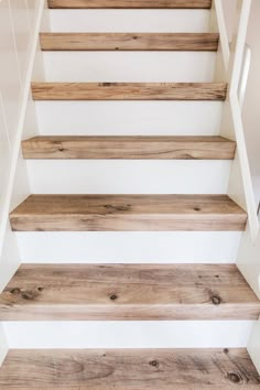 some wooden stairs in a house with white walls and wood flooring on the bottom