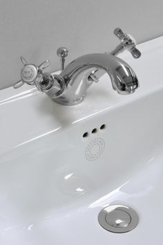 a white sink with chrome faucet and soap dispenser