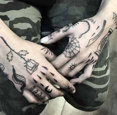 two hands with tattoos on them are sitting next to each other, one is holding the other