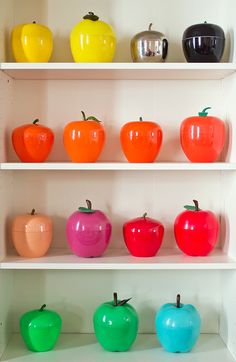 there are many different colored apples on the shelves