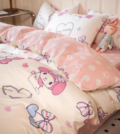 a bed with pink and white sheets, pillows and stuffed animals on the headboard