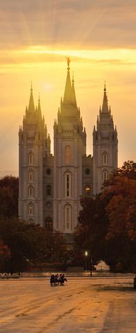 the sun is setting in front of a large building with towers and spires on it