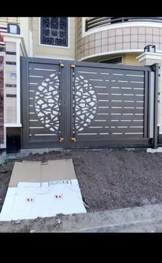 an iron gate in front of a house that is being built on the side of a road