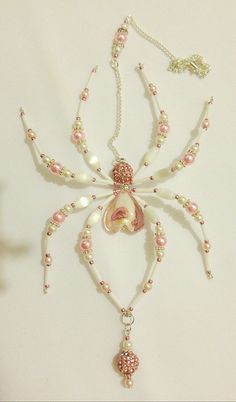 a white and pink necklace with pearls, beads and a flower on it's side